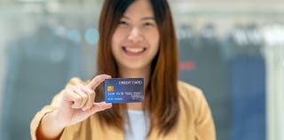 A woman holding a Hilton Honors Surpass card in front of her.